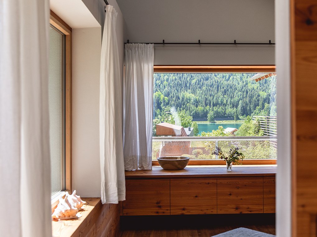 Ferienwohnung 4FLOSSE am Weissensee – Wohnzimmer mit Vertäfelung und Blick zum See