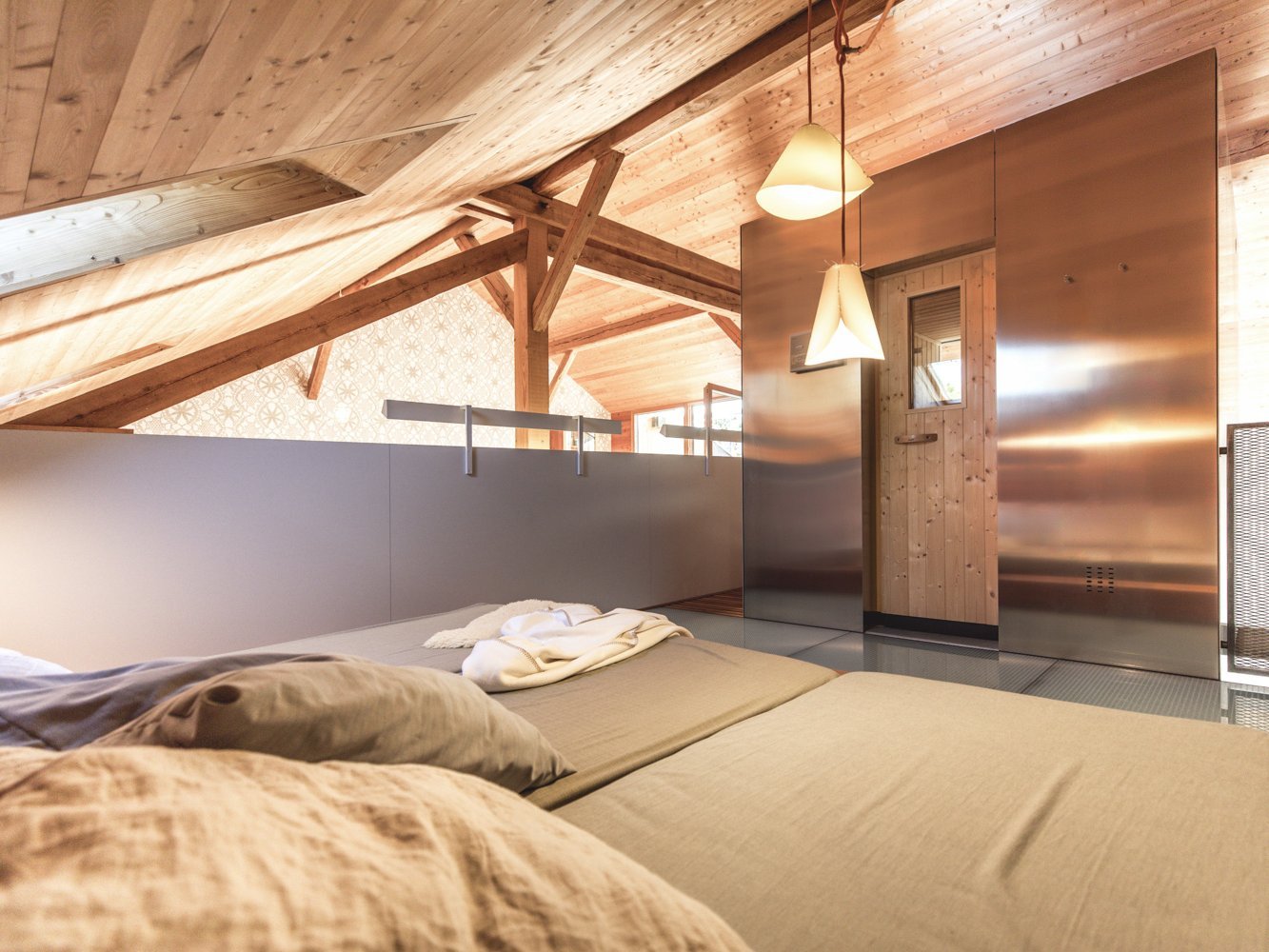 Ferienwohnung 3HECK am Weissensee – Wohnraum mit Tagesbett, Lärchenholzvertäfelung und Natursteinboden