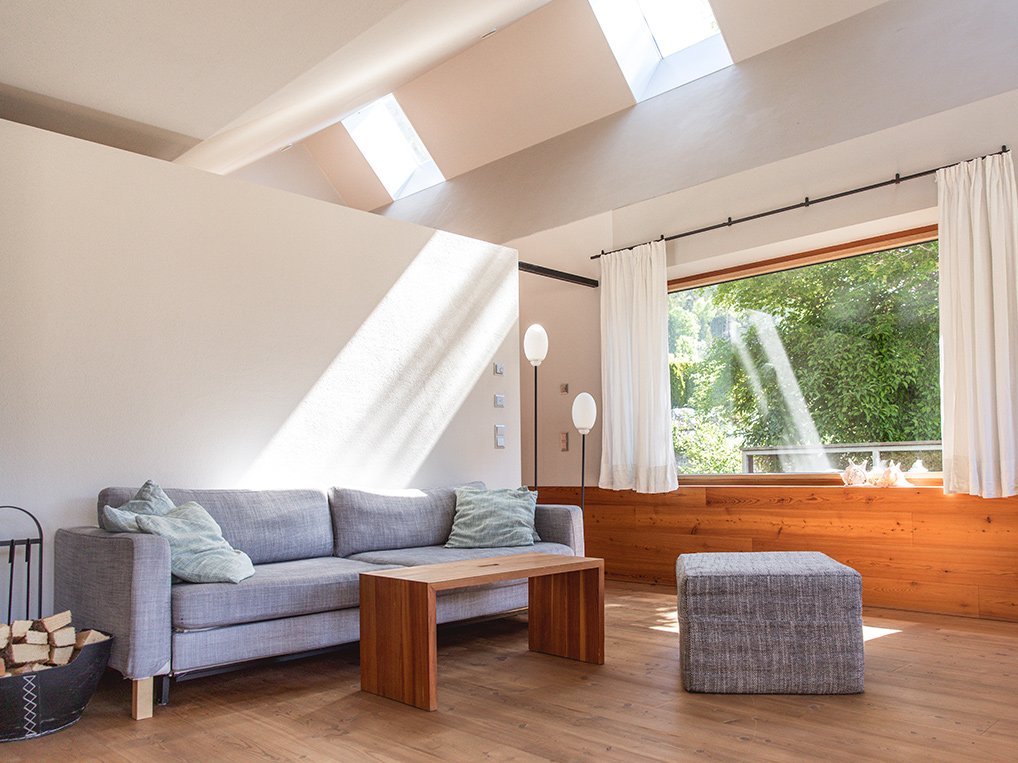 Ferienwohnung FLOSSE am Weissensee – Wohnbereich mit geölter Lärchenholzvertäfelung und Natursteinboden