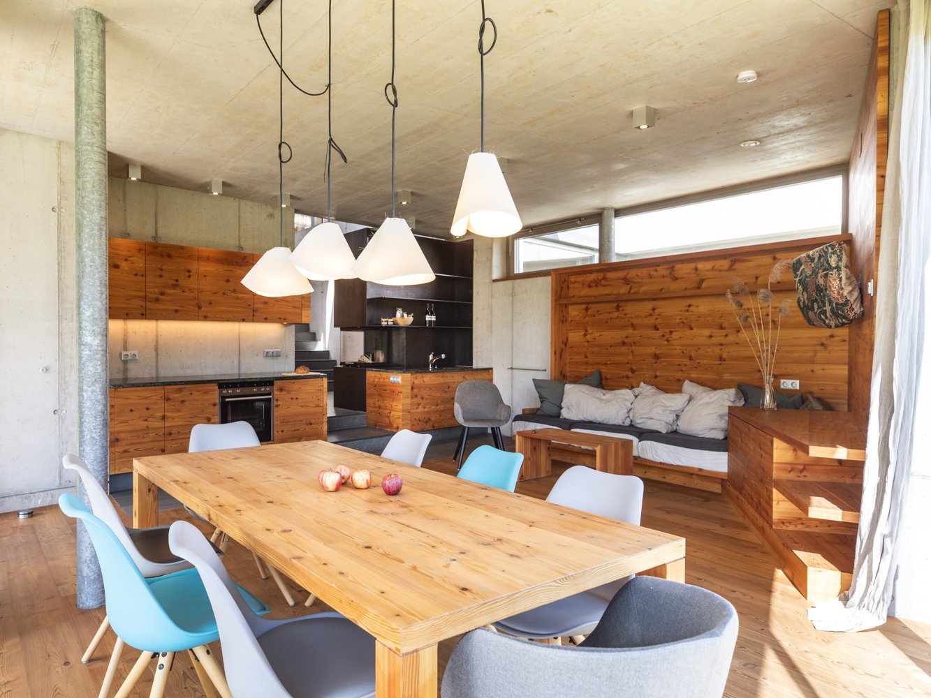 Ferienwohnung 5BOJE Chalet Wohnbereich mit zentralem rundum verglasten Kaminofen und großen Tischen